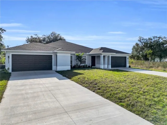 View of front of home featuring concrete driveway, a front lawn, stucco siding, and an attached garage