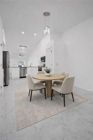 Dining space with light marble finish flooring and lofted ceiling