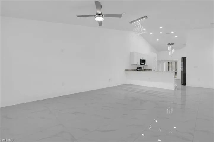 Unfurnished living room with light marble finish floors, high vaulted ceiling, recessed lighting, and ceiling fan