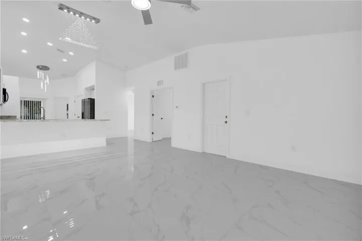 Unfurnished living room featuring light marble finish floors, high vaulted ceiling, and a ceiling fan
