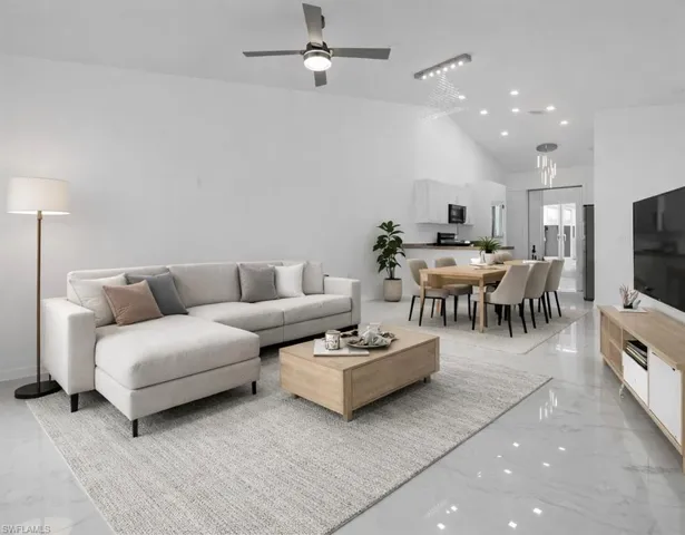 Living room with lofted ceiling, light marble finish flooring, recessed lighting, and a ceiling fan
