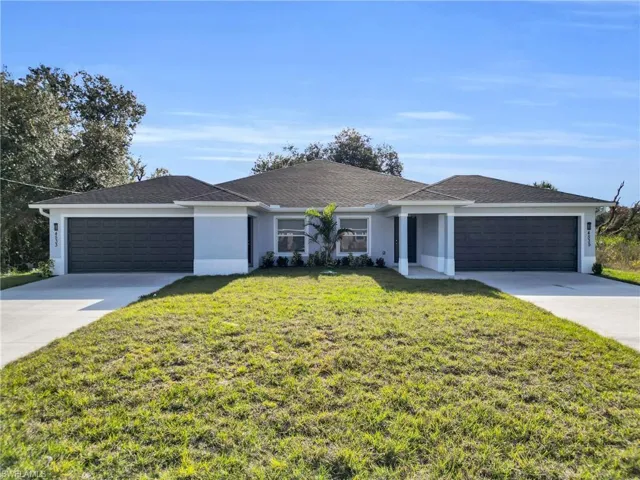 Ranch-style home with stucco siding, a front lawn, driveway, a garage, and roof with shingles