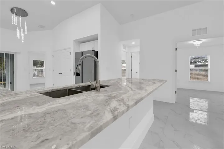 Kitchen with plenty of natural light, light marble finish flooring, white cabinetry, light stone countertops, and recessed lighting
