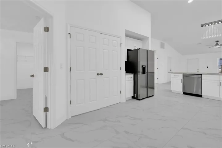 Kitchen with white cabinetry, light marble finish floors, appliances with stainless steel finishes, ceiling fan, and high vaulted ceiling