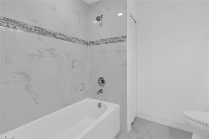 Bathroom featuring marble finish flooring and shower / bathtub combination