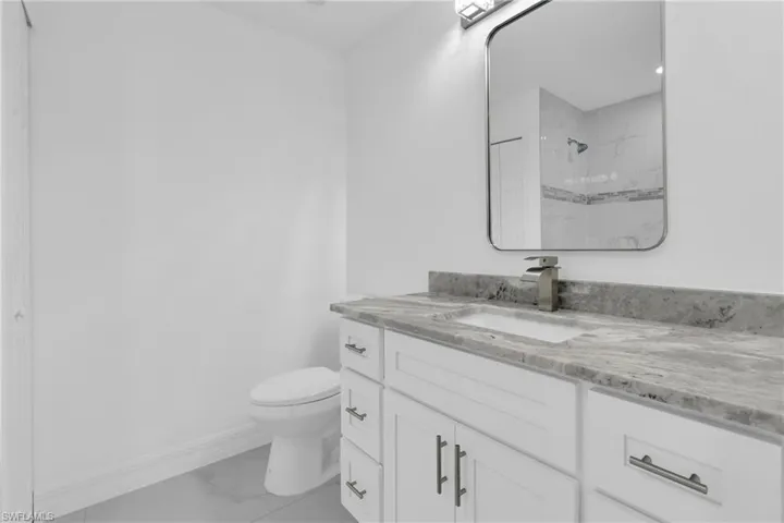 Full bathroom with light marble finish flooring, a marble finish shower, and vanity