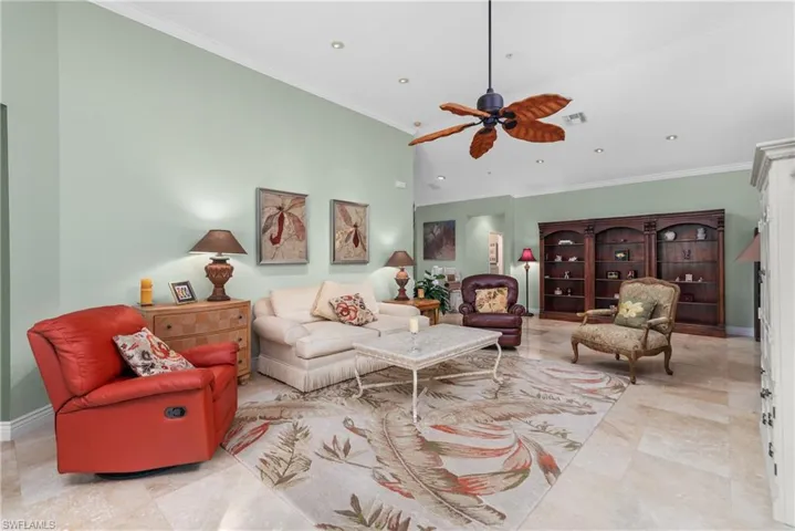 Tiled living room with a towering ceiling, ornamental molding, and ceiling fan