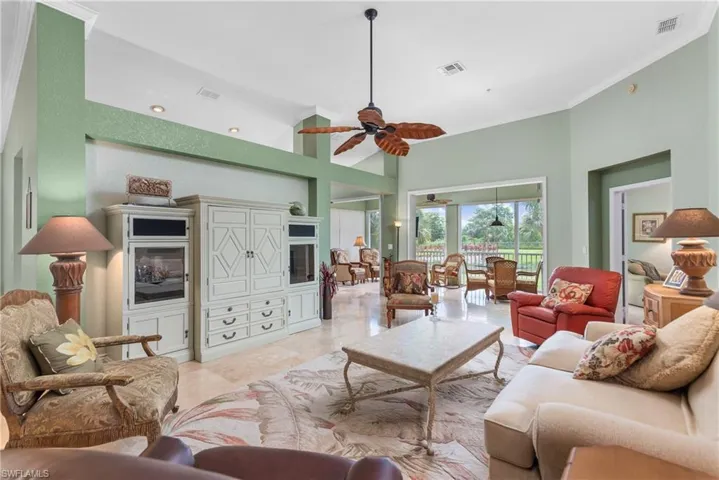 Living room featuring light tile patterned flooring, a high ceiling, ceiling fan, and ornamental molding