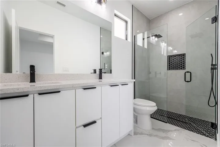 Bathroom with double vanity, a stall shower, and light marble finish floors