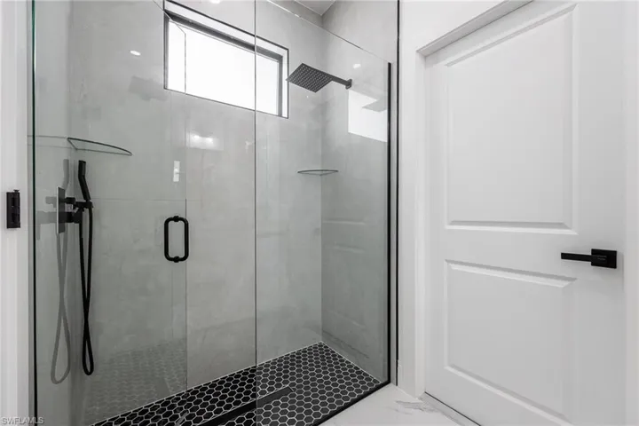 Bathroom with a stall shower and light marble finish floors