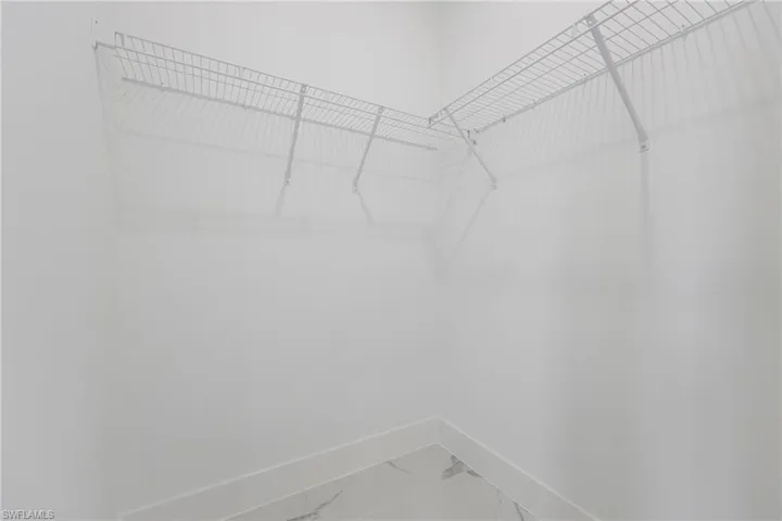 Walk in closet featuring light marble finish floors