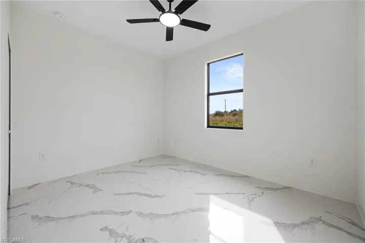 Empty room featuring light marble finish floors and ceiling fan