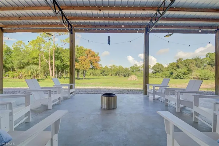 Patio terrace at dusk featuring an outdoor fire pit, a patio, and view of scattered trees