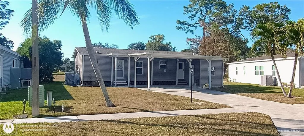 Manufactured / mobile home featuring a front lawn, driveway, and a carport