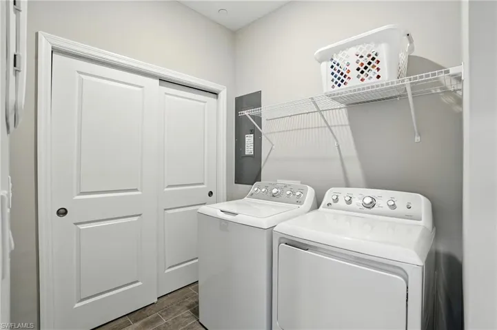 Laundry area with wood finish floors, separate washer and dryer, and electric panel