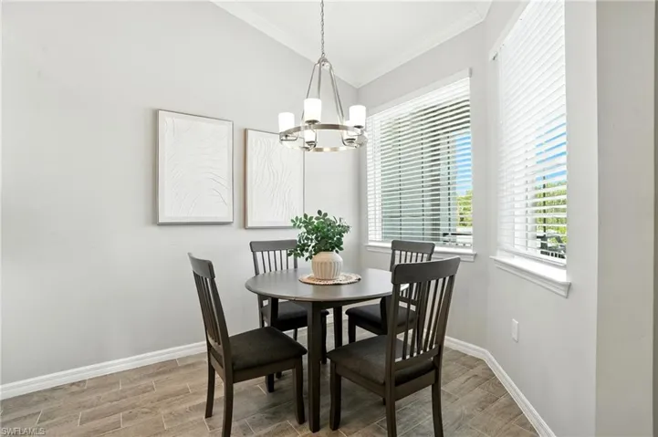 Dining room with wood finish floors, crown molding, and a chandelier