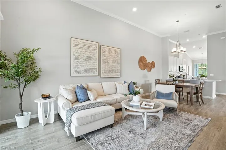 Living room with light wood-type flooring, crown molding, a chandelier, and recessed lighting