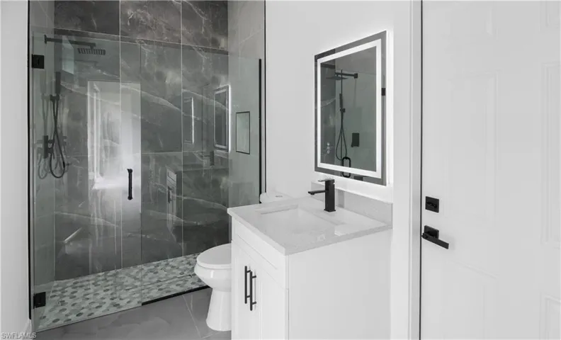 Bathroom with vanity and a marble finish shower