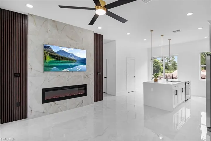 Living area with a fireplace, recessed lighting, light marble finish floors, and ceiling fan