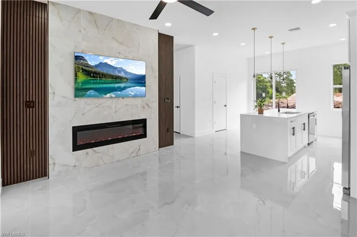 Living room with a fireplace, recessed lighting, a ceiling fan, and light marble finish flooring