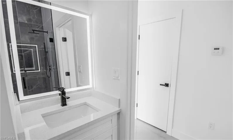 Bathroom featuring vanity and a marble finish shower
