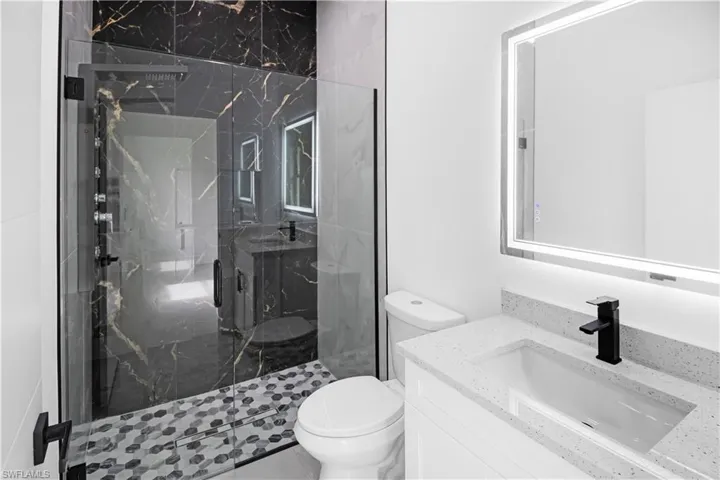 Full bath featuring vanity and a marble finish shower