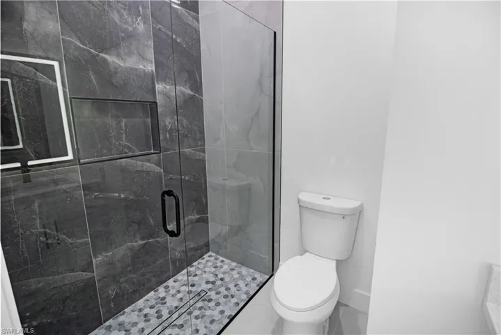 Full bath featuring toilet and a marble finish shower