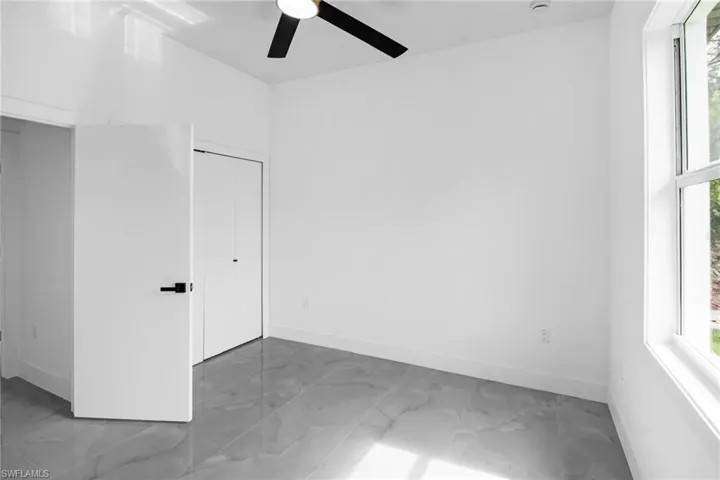 Unfurnished bedroom with light marble finish flooring, a ceiling fan, and a closet