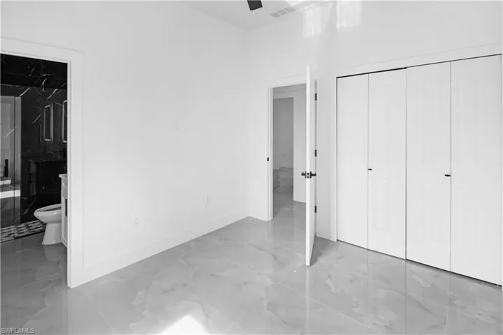 Unfurnished bedroom featuring light marble finish floors, ensuite bath, and a closet