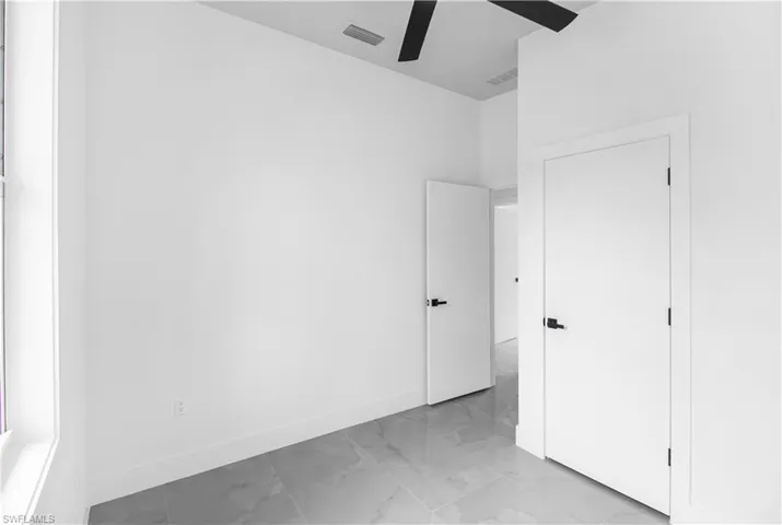 Unfurnished bedroom with light marble finish floors and a ceiling fan