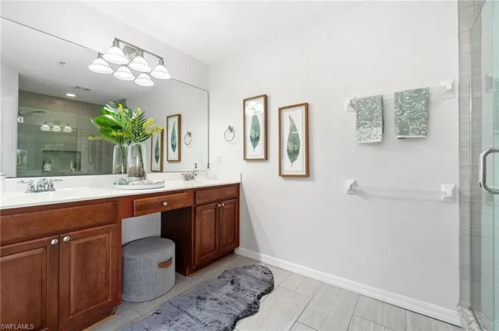 Primary bathroom with tile patterned floors, an enclosed shower, and dual bowl vanity