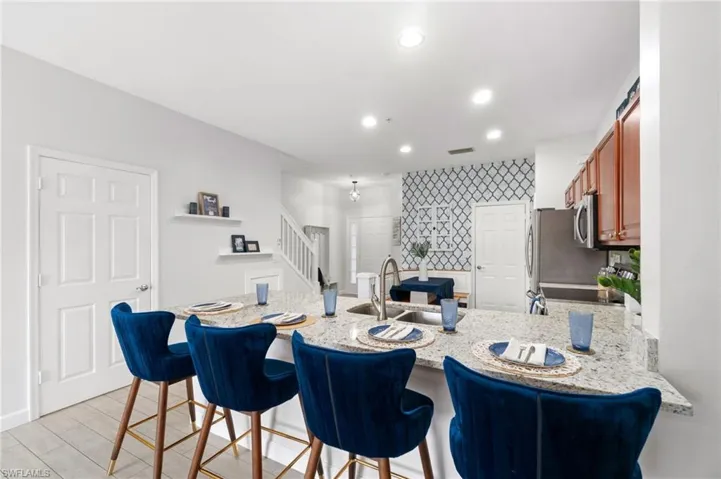 Kitchen featuring range, kitchen peninsula, light stone counters, sink, and a kitchen bar