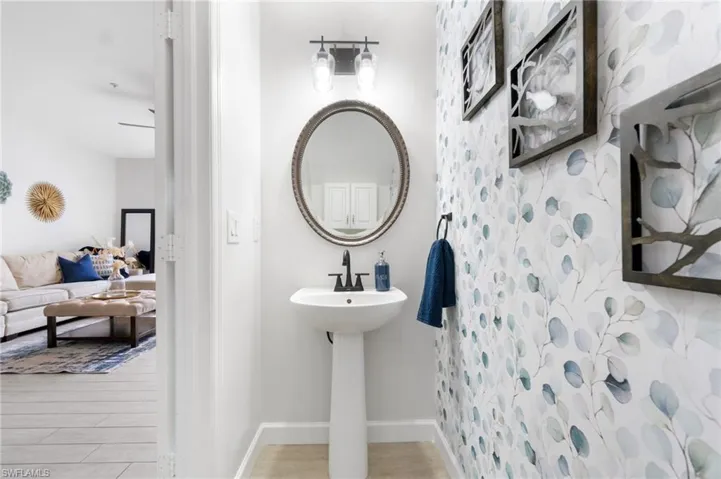 Downstairs half bath featuring decorative papered wall and pedestal sink