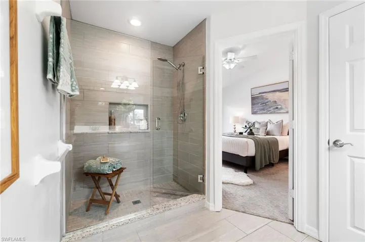 Primary bathroom with a shower with shower door, ceiling fan, and tile patterned floors
