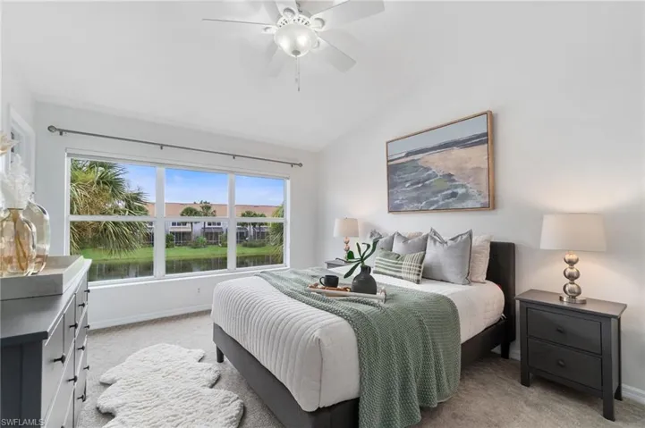 Primary bedroom featuring ceiling fan, lofted ceiling, and light colored carpet