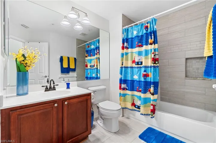 Full bathroom featuring tile patterned floors, shower / bath combination with curtain, toilet, and vanity