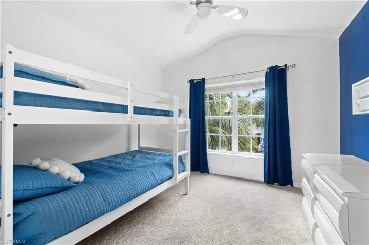 Guest Bedroom 1 featuring carpet floors, ceiling fan, and vaulted ceiling