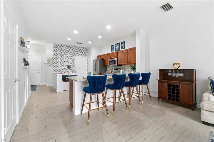 Kitchen featuring stainless steel appliances, kitchen peninsula, backsplash, light wood-type flooring, and a kitchen breakfast bar
