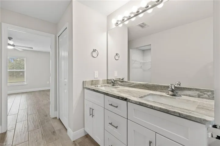 Bathroom featuring dual vanity, ceiling fan, and hardwood / wood-style flooring