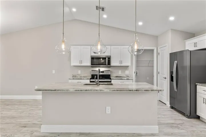 Kitchen featuring light hardwood / wood-style floors, a center island with sink, and stainless steel appliances
