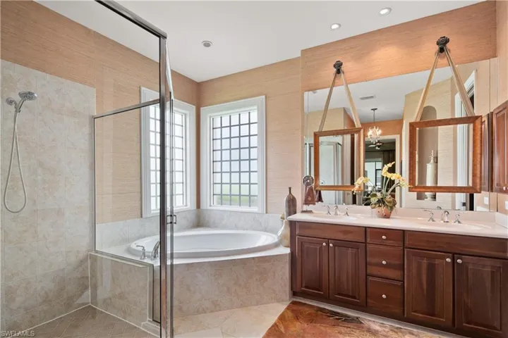 Bathroom featuring tile patterned floors, double sink vanity, a chandelier, and plus walk in shower