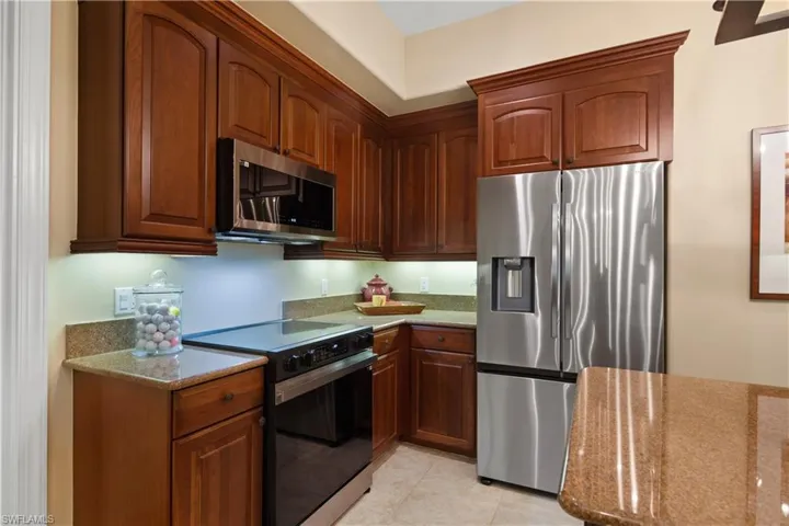 Kitchen with appliances with stainless steel finishes, light tile patterned floors, and light stone countertops