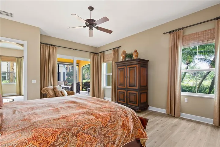Bedroom with light hardwood / wood-style floors, multiple windows, ceiling fan, and access to exterior