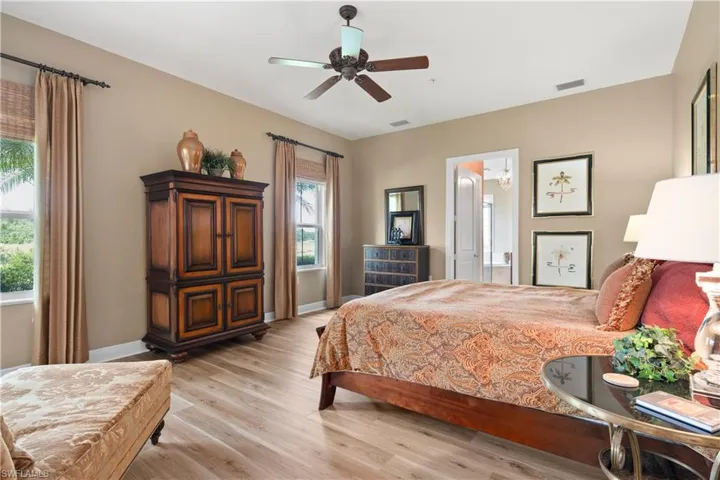 Bedroom featuring ensuite bath, light wood-type flooring, and ceiling fan
