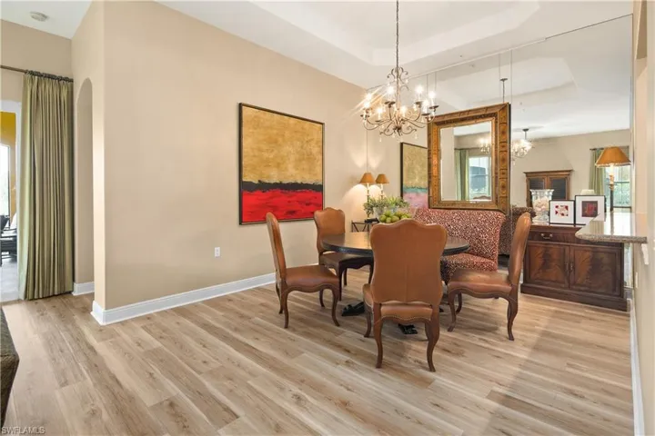 Dining space with light hardwood / wood-style floors, an inviting chandelier, and a raised ceiling