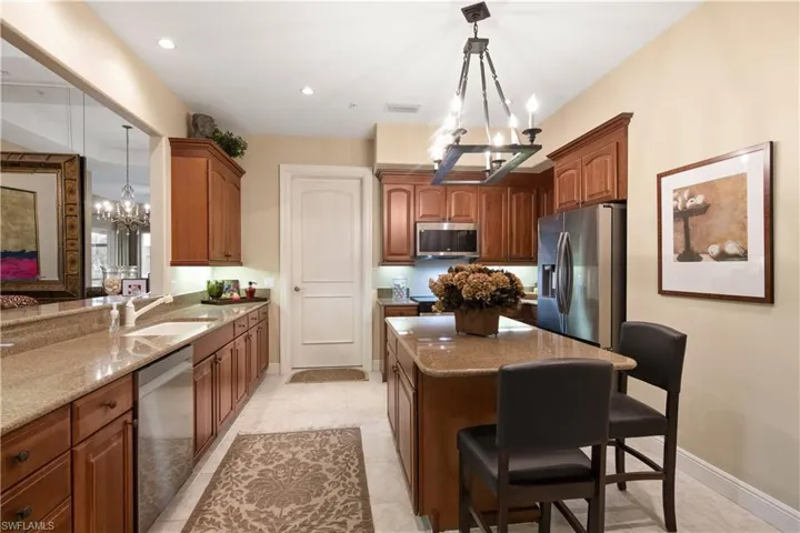 Kitchen featuring light tile patterned flooring, sink, appliances with stainless steel finishes, and a notable chandelier