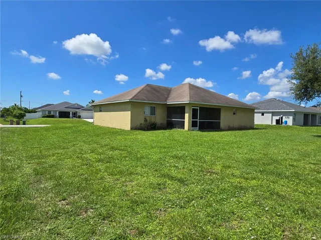 Back of house with a sunroom, stucco siding, and a yard