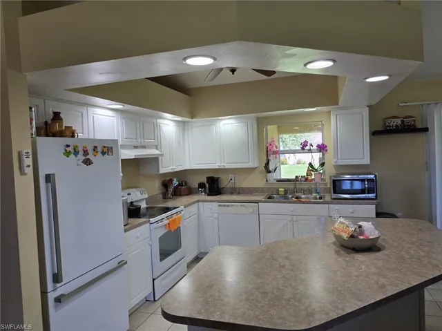 Kitchen with white appliances, white cabinetry, light tile patterned floors, and recessed lighting