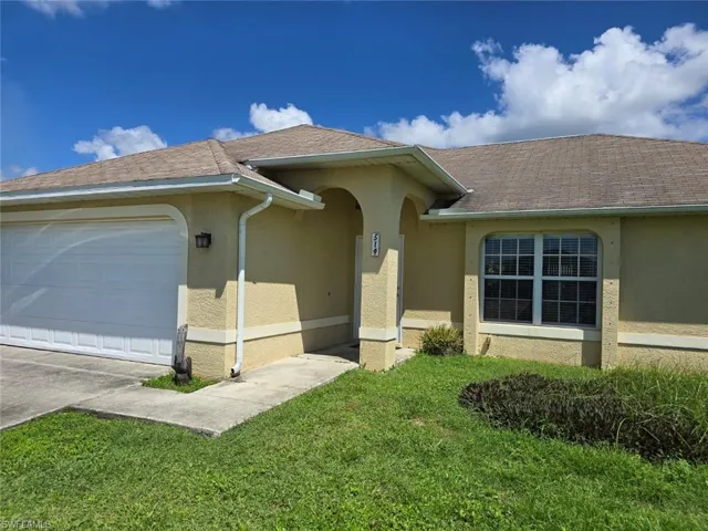 View of front of house with an attached garage, stucco siding, a shingled roof, and a front lawn