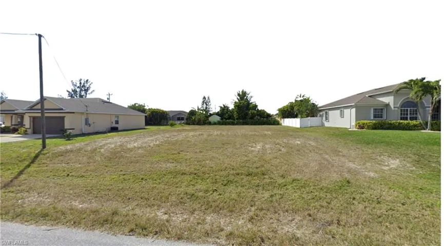 View of yard featuring driveway, a garage, and fence